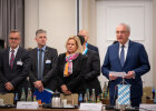 Herrmann Faeser und weitere Personen stehend vor dem Besprechungstisch