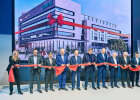 Gruppenfoto mit Schere und Band vor einer Projektion des neuen Empfangsgebäudes