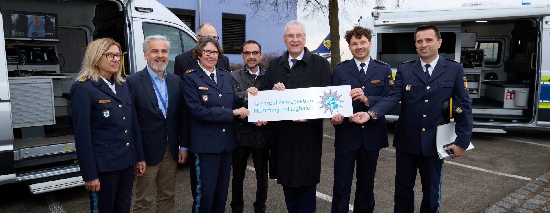 Innenminister Herrmann mit Polizeipräsidentin Dr. Claudia Strößner und weiteren mit symbolischem Schild zur neuen Grenzpolizeiinspektion Memmingen-Flughafen.