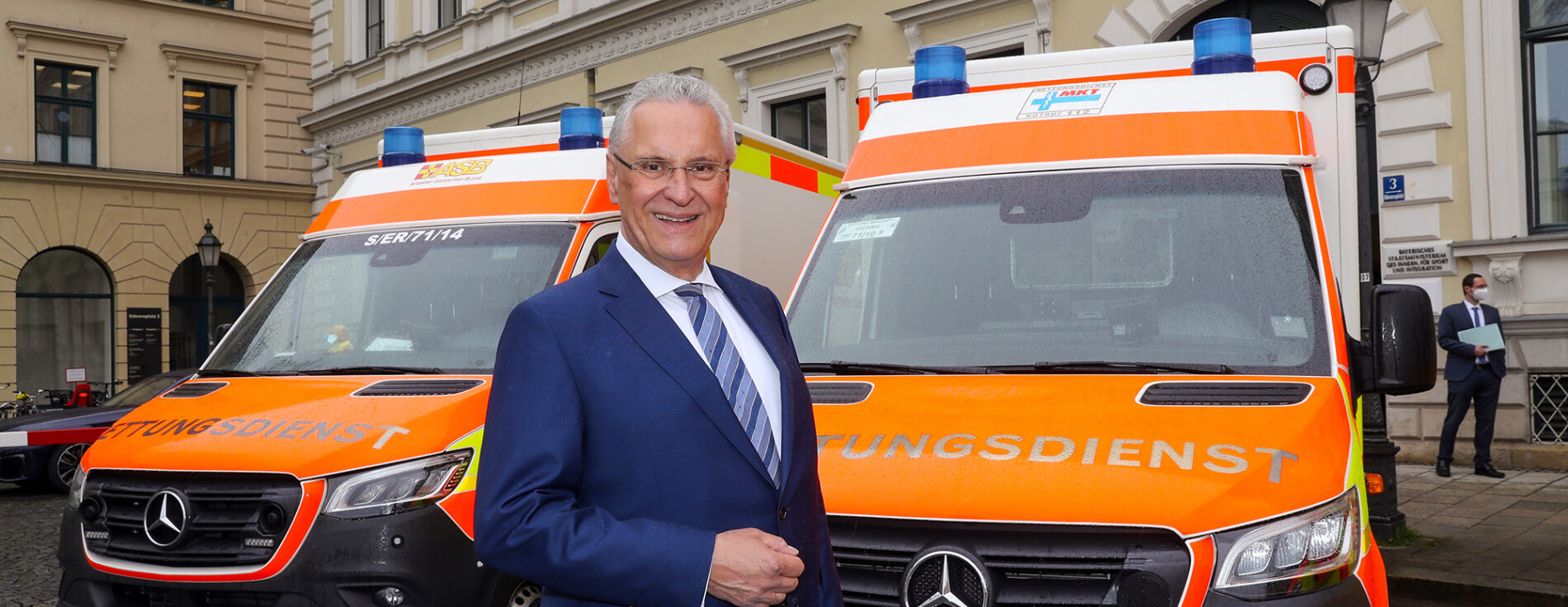 Innenminister Joachim Herrmann vor Rettungsdienst-Fahrzeugen vor dem Innenministerium
