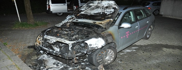 Das Foto zeigt einen PKW, dessen Motorhaube geöffnet ist und der Motorraum durch einen Brand stark zerstört wurde